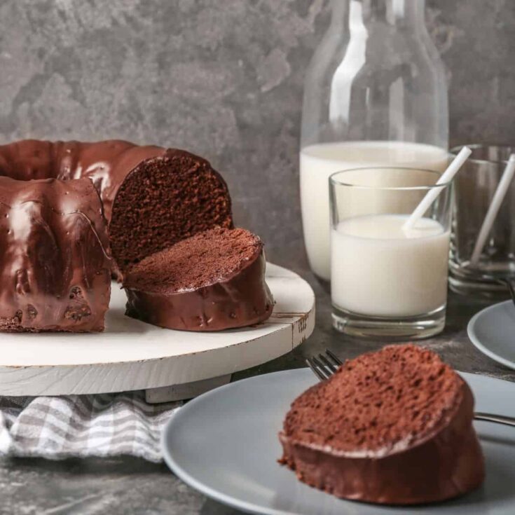 Chocolate Brownie Cake on plate and wooden cake stand with glass of milk.