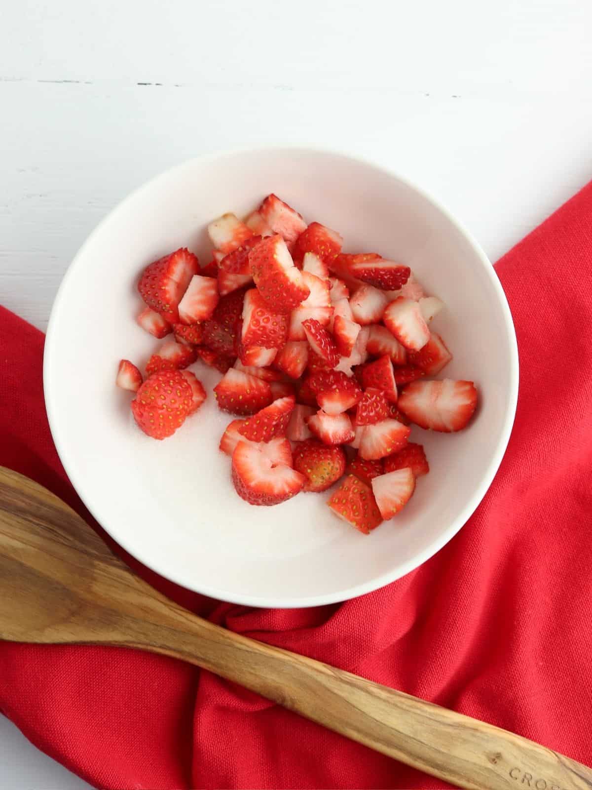 Sliced strawberries with sugar in bowl.