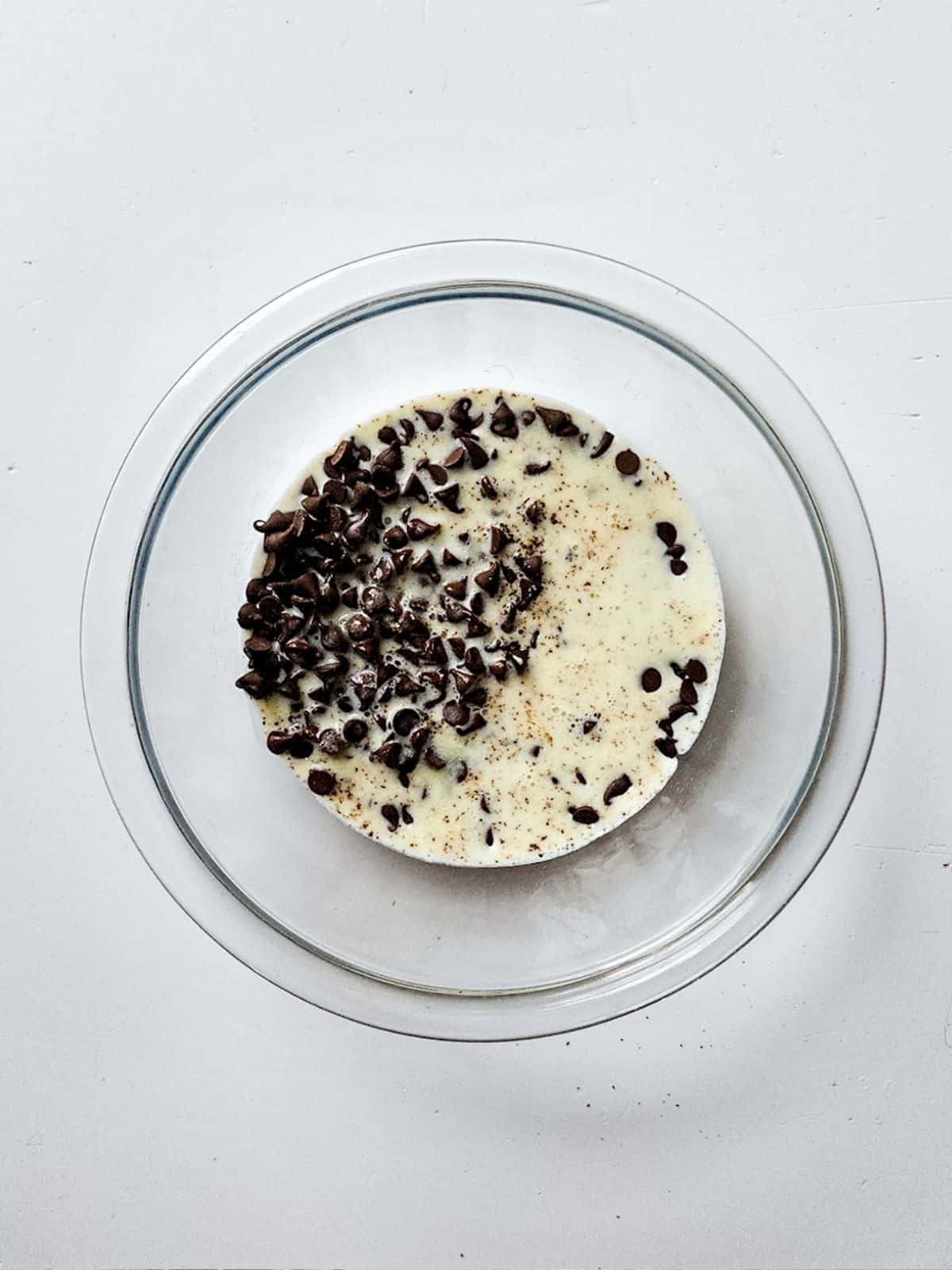 chocolate chips with heavy whipping cream in glass bowl.