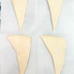 crescent roll triangles on parchment paper.