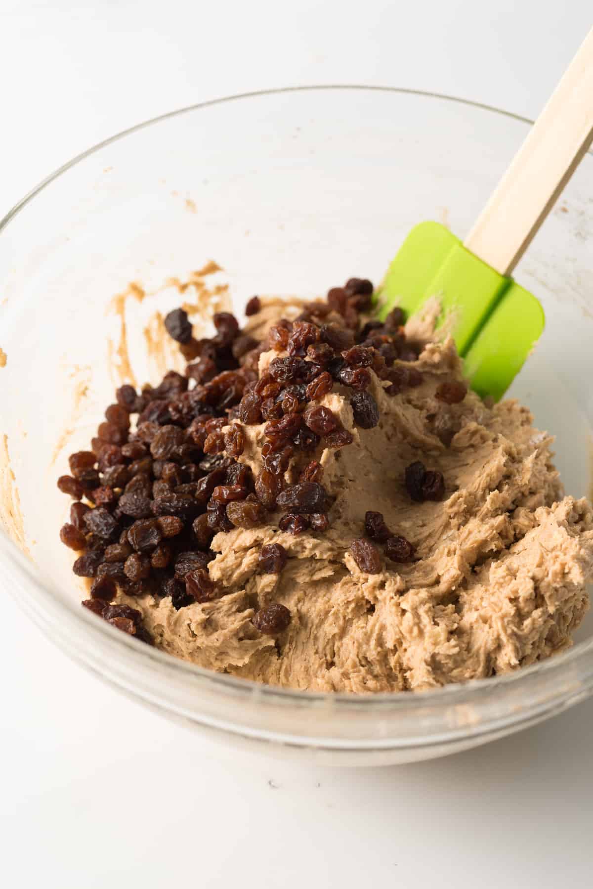 Oatmeal cookie dough batter with raisins in glass bowl.