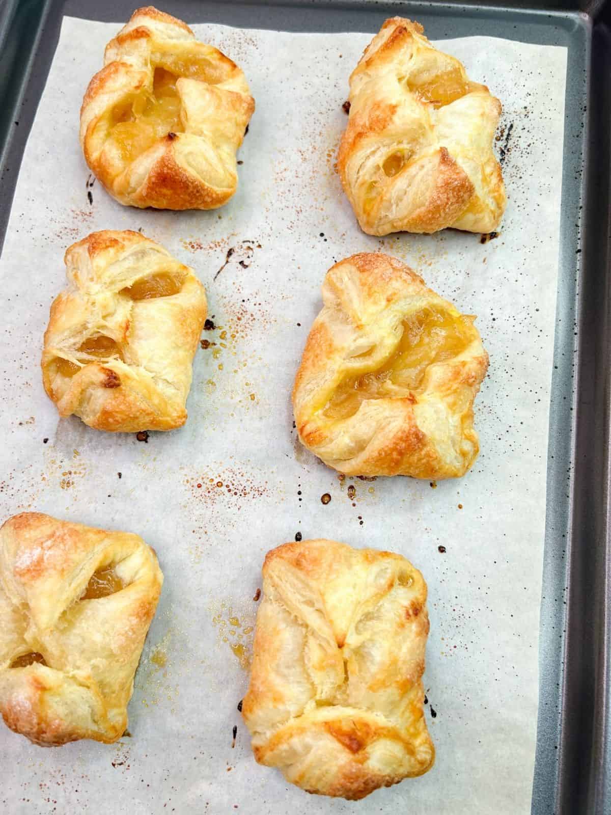 baked apple danishes on a parchment line baking tray