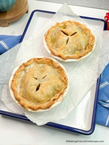 Baked apple pie for two on tray with parchment paper.