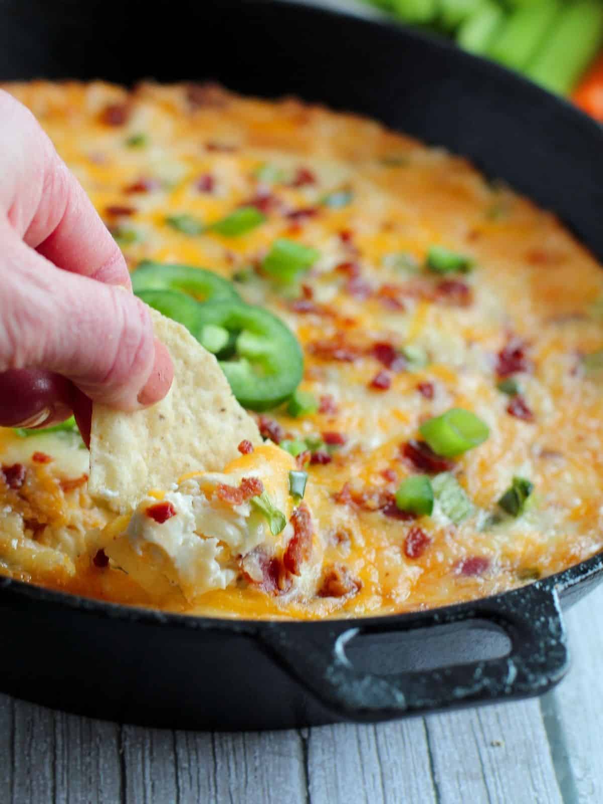 dipping chip into baked jalapeno dip.