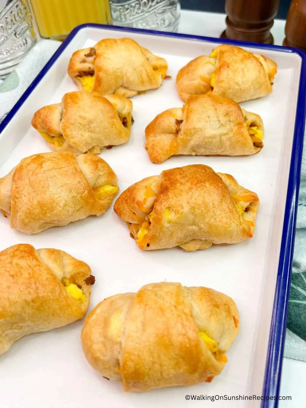 baked crescent rolls on serving tray stuffed with scrambled eggs and browned sausage.