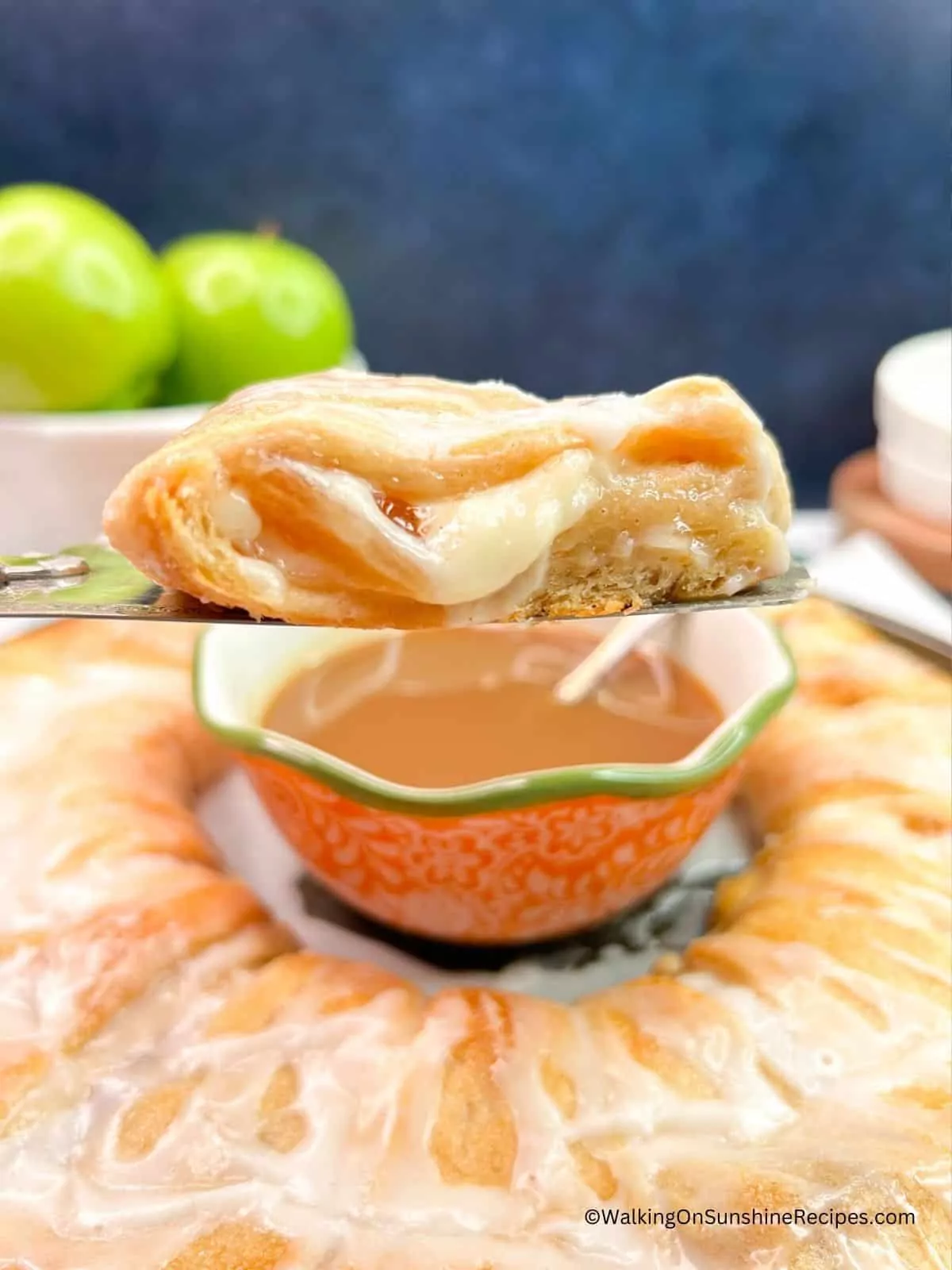 Slice of crescent rolls with apple pie filling on serving spatula.