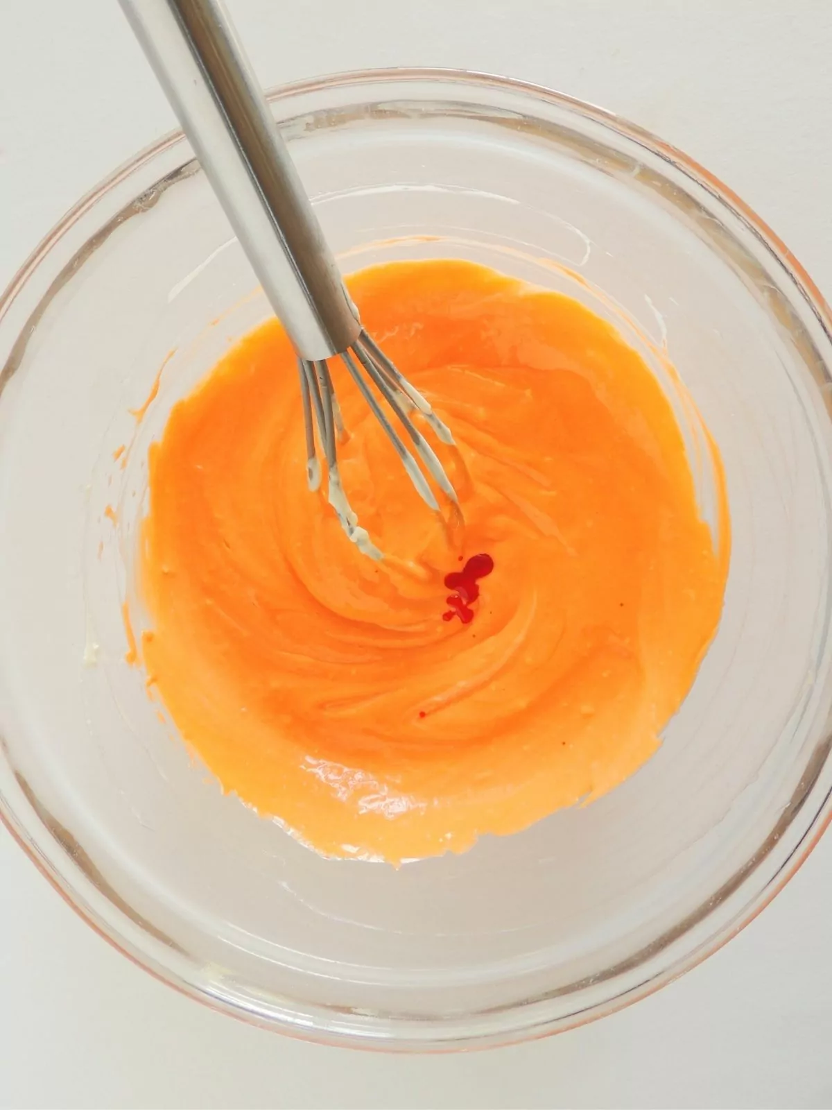 Orange frosting in glass bowl.