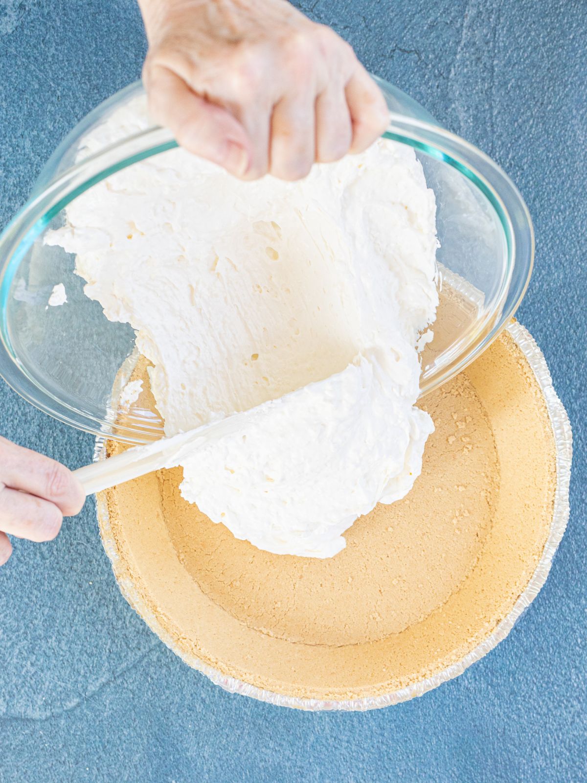 Adding no bake cheesecake mixture to graham cracker crumb pie crust.