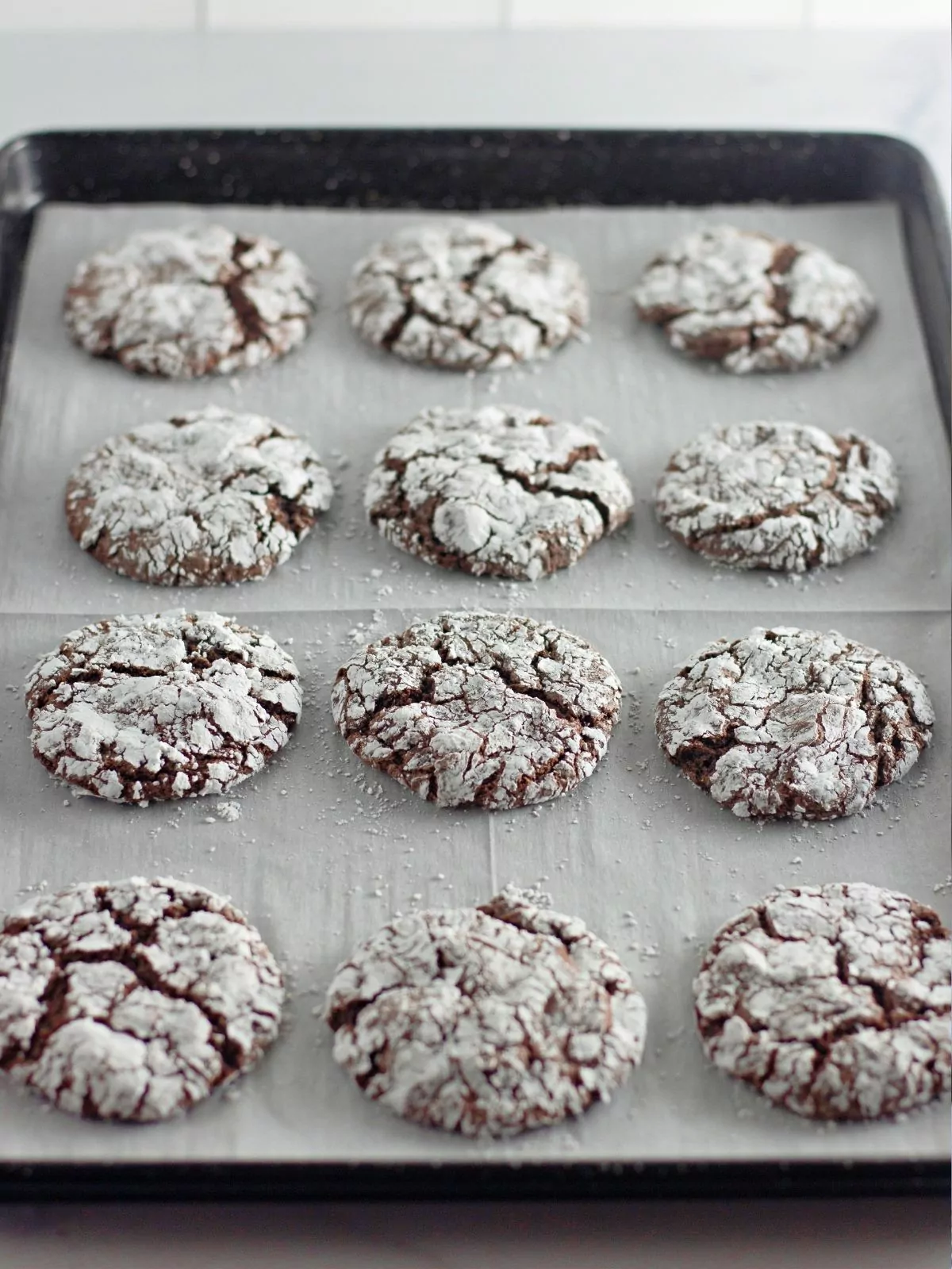 baked chocolate cake mix cookies on baking tray with parchment paper.