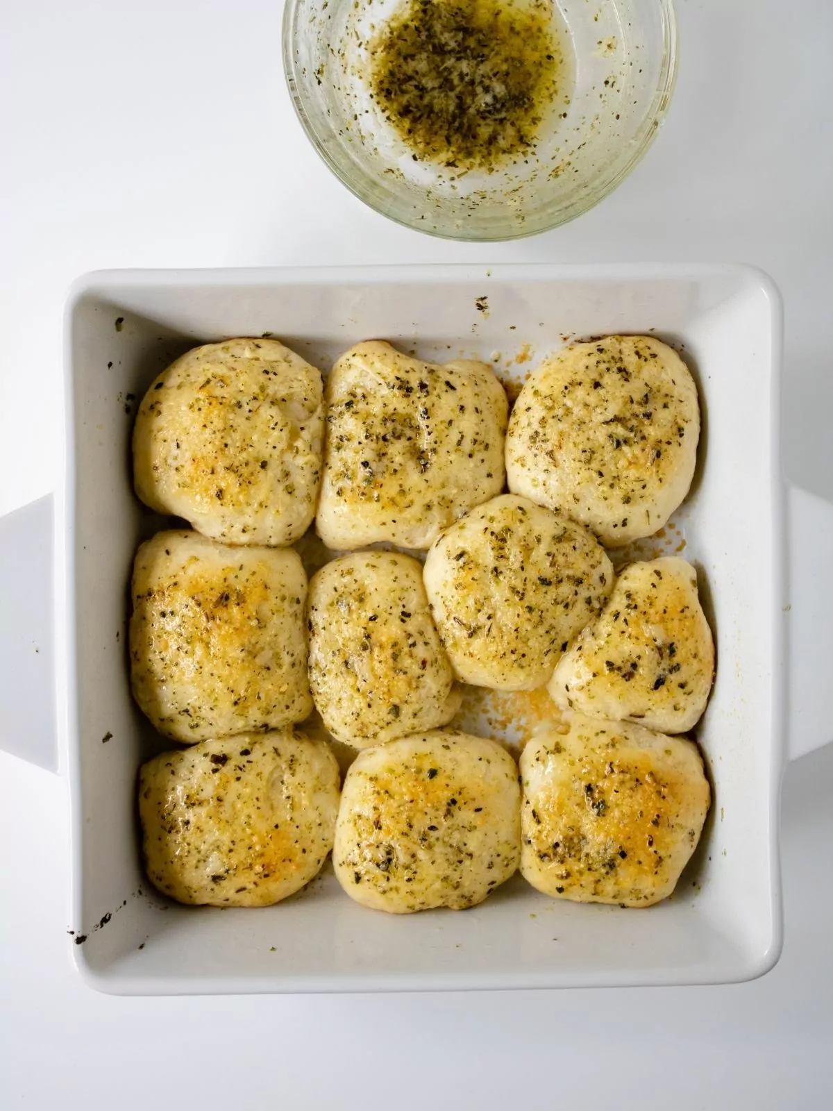 Baked refrigerator dough with melted garlic butter in casserole dish.