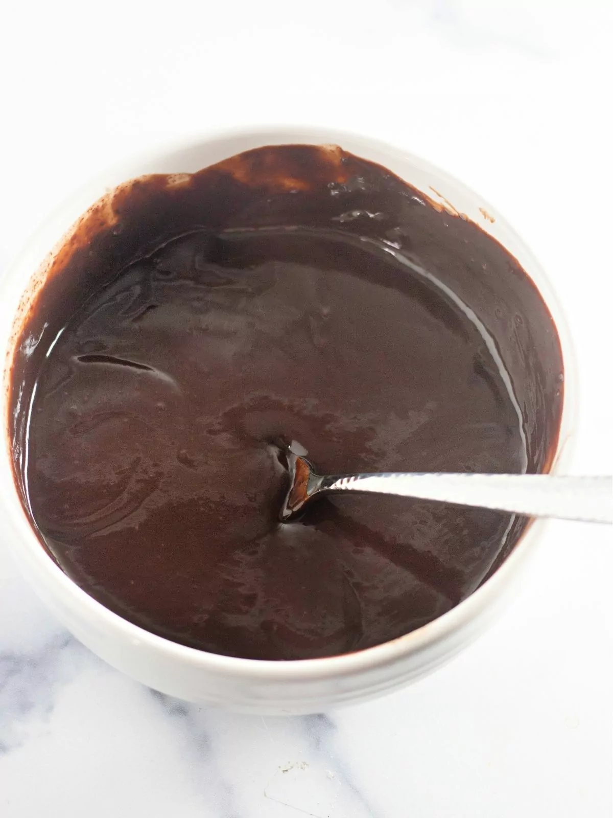 heavy cream melted chocolate mixture in bowl with spoon.