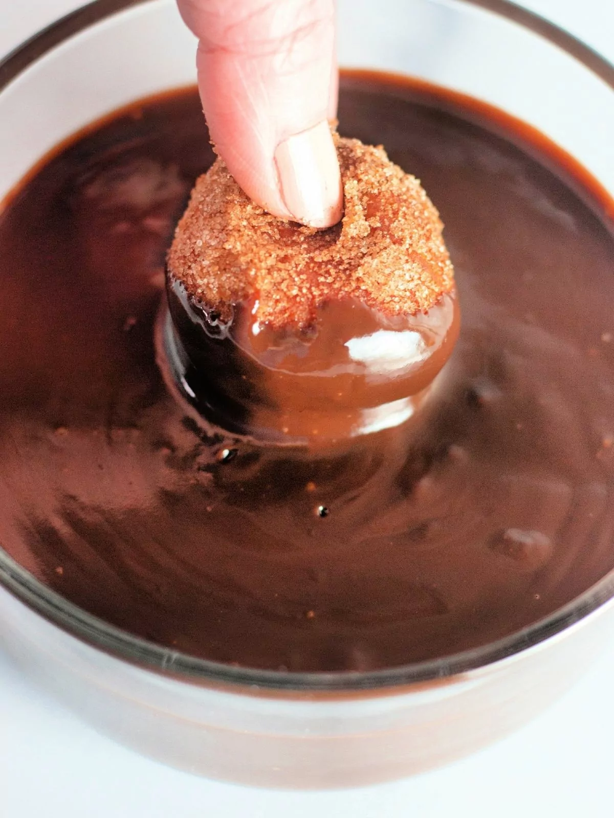 dipping donut hole in melted chocolate.