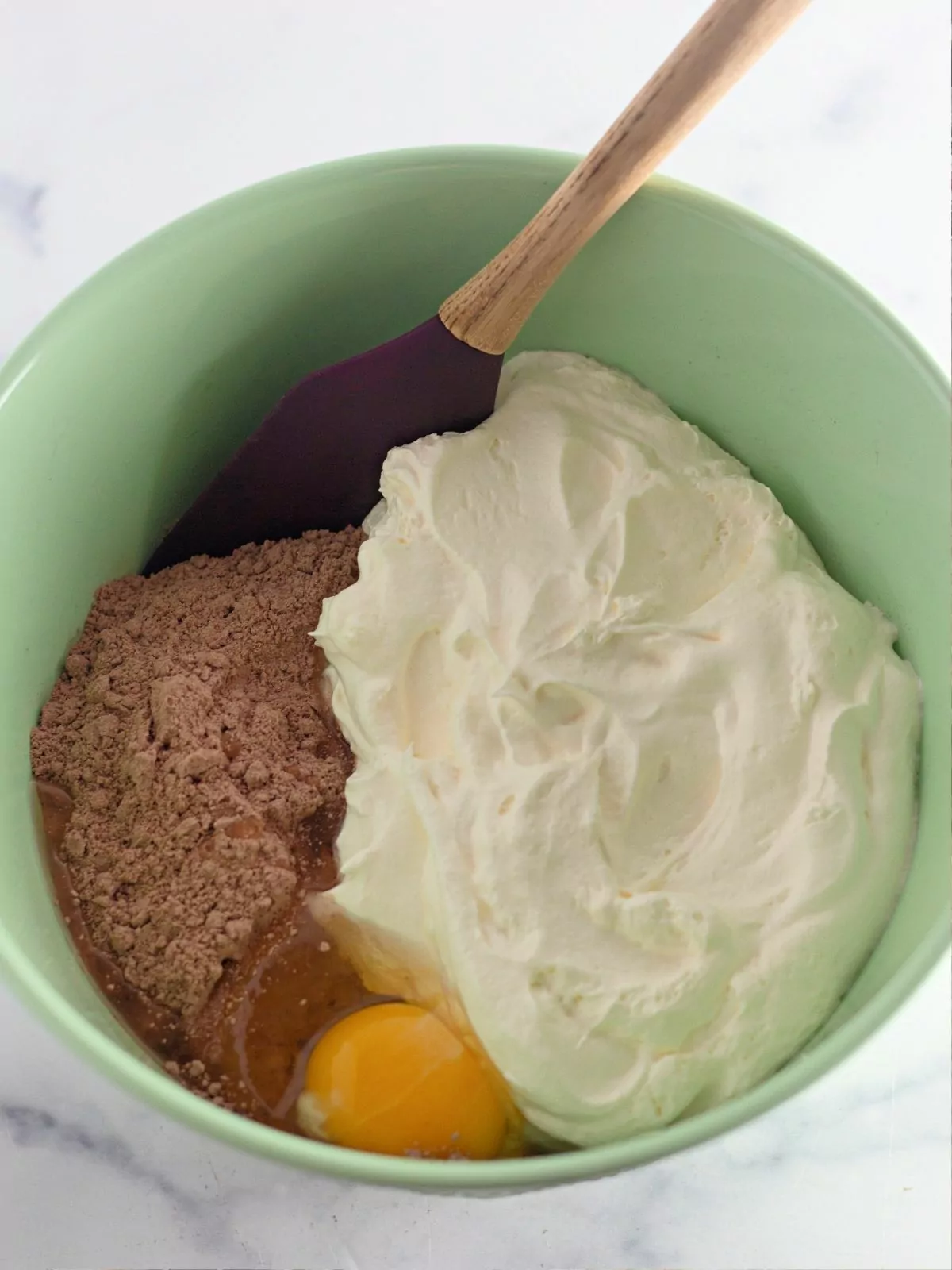 Cake Mix cookie ingredients in green bowl with wooden spoon.