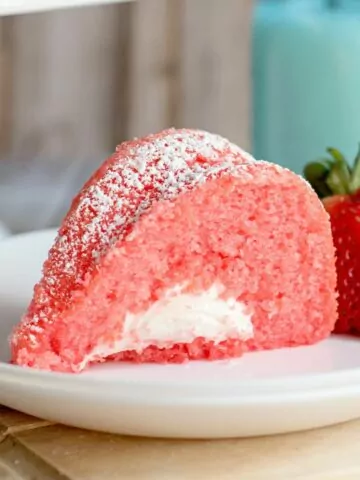 piece of strawberry cake with marshmallow filling on white plate with fresh strawberries.