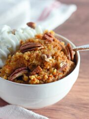 White bowl filled with pumpkin cobbler and whipped cream.