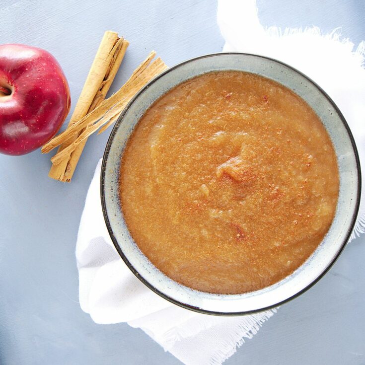 bowl of applesauce with apple on the side.