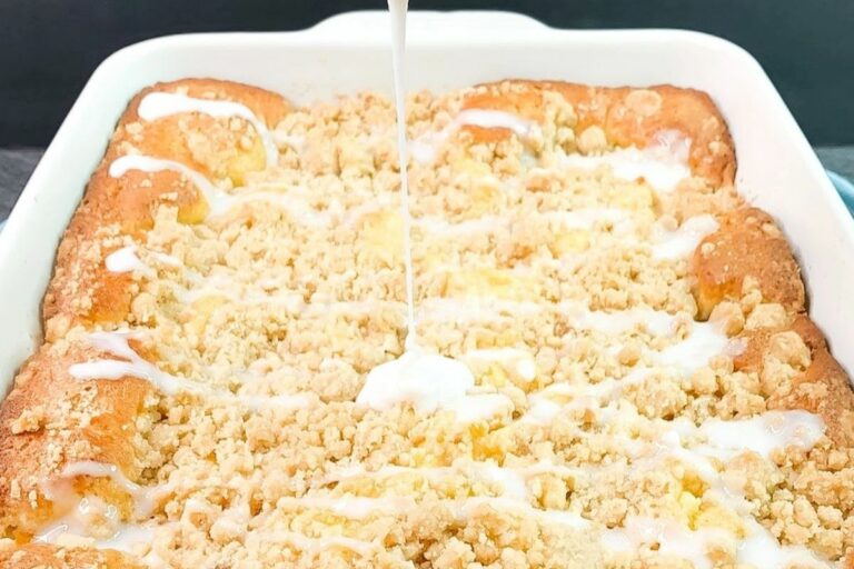 A baking dish of monkey bread with a glaze being drizzled on top.