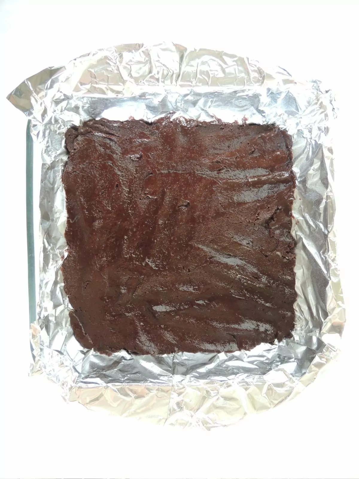 brownie batter in pan with aluminum foil.