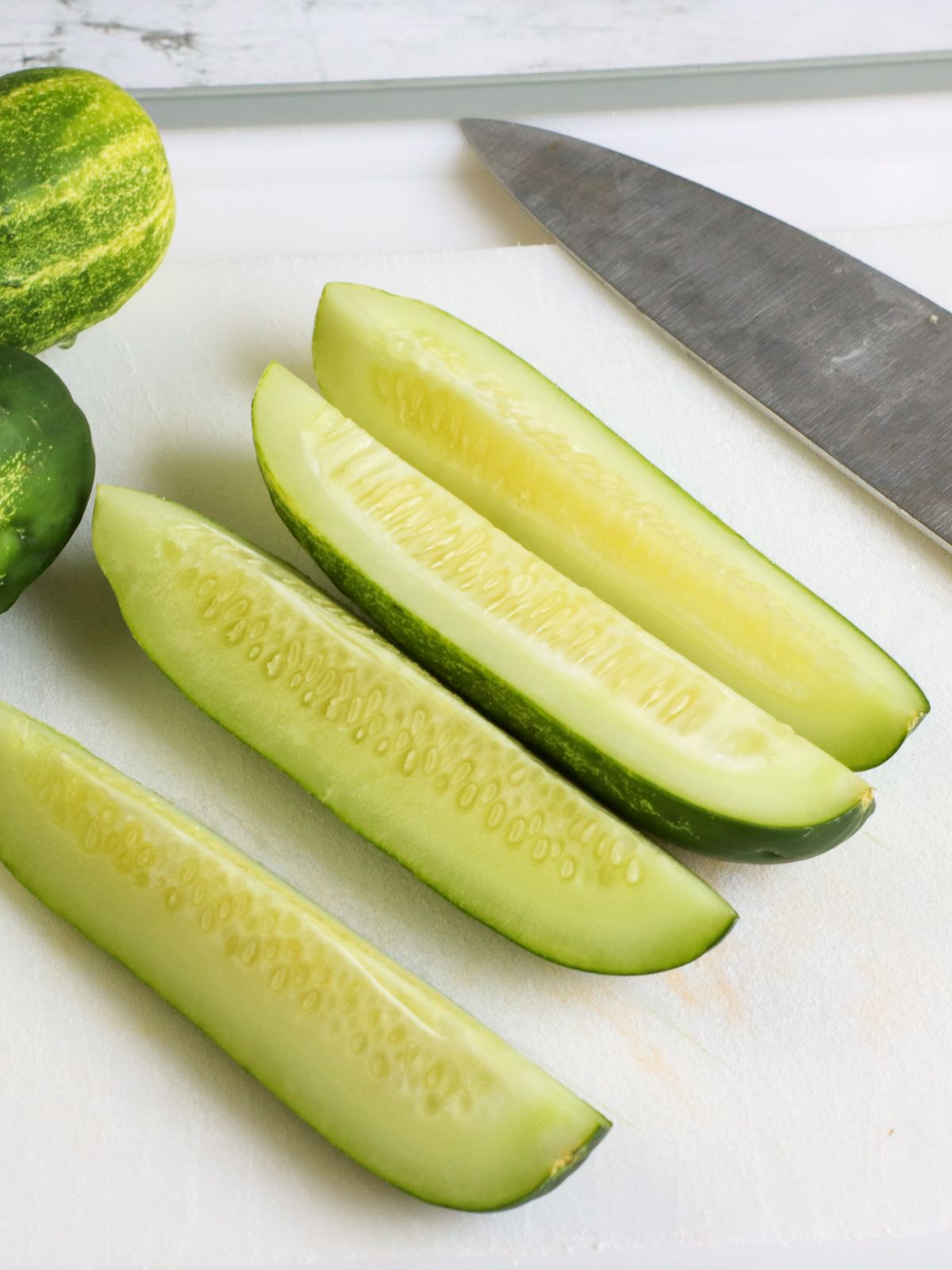 Sliced cucumbers on cutting board.