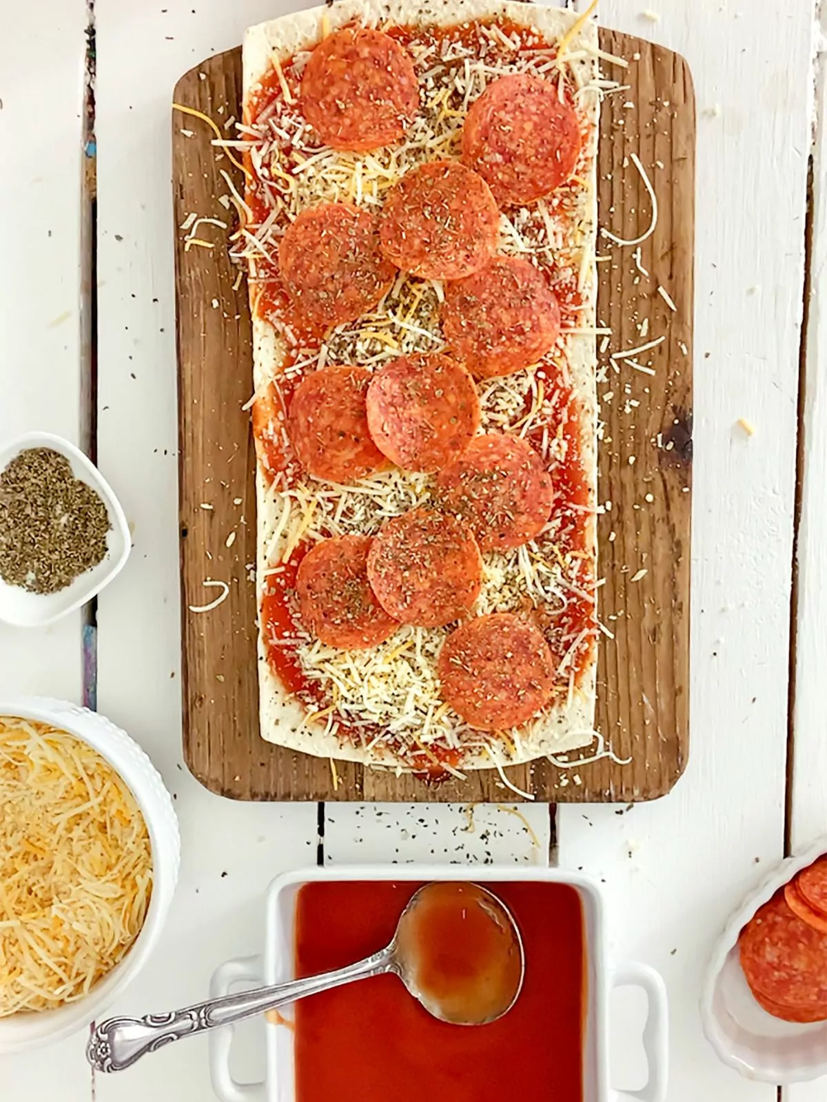 unbaked pepperoni pizza made with naan bread on cutting board.