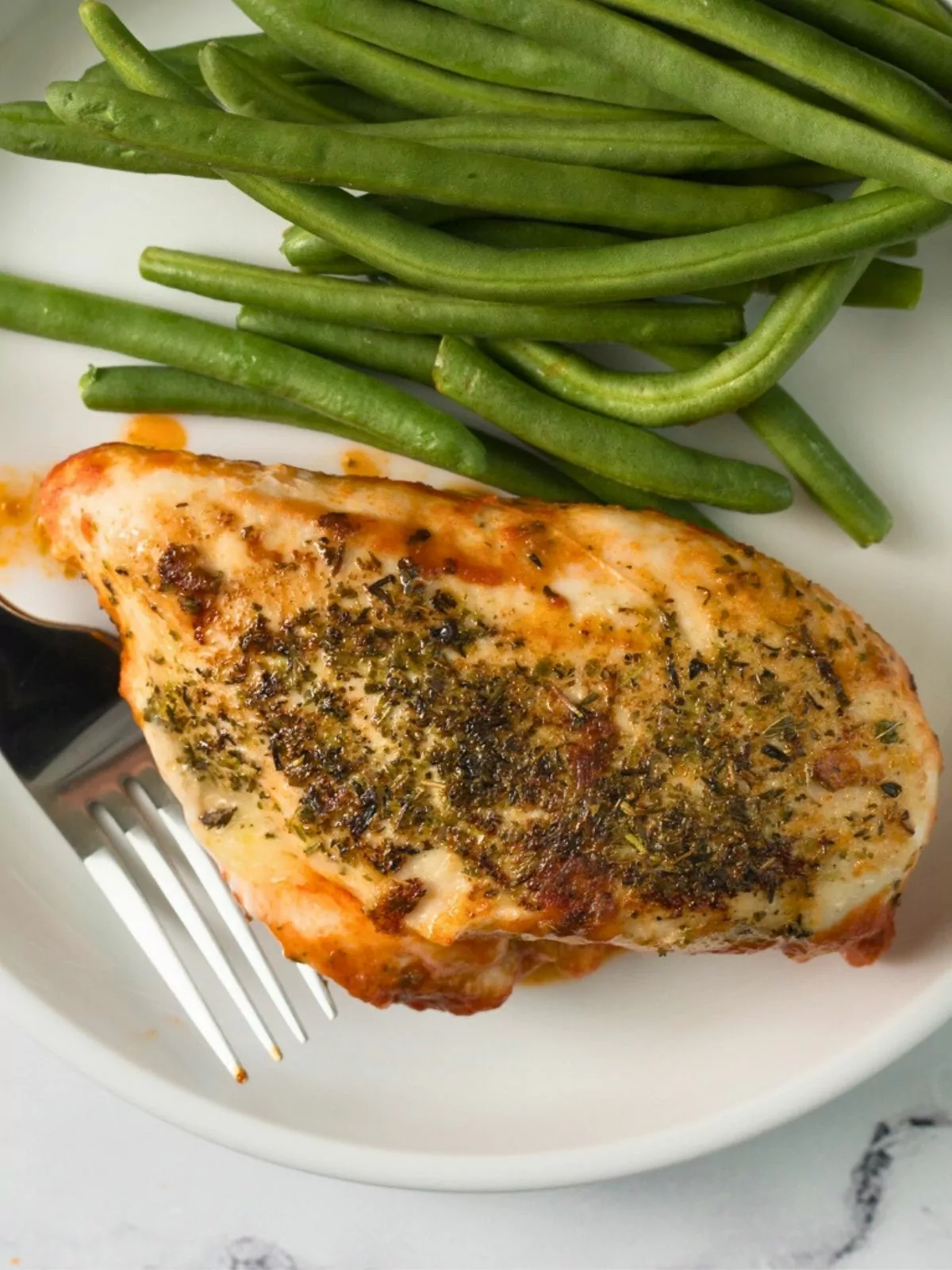 chicken breast on plate with green beans.