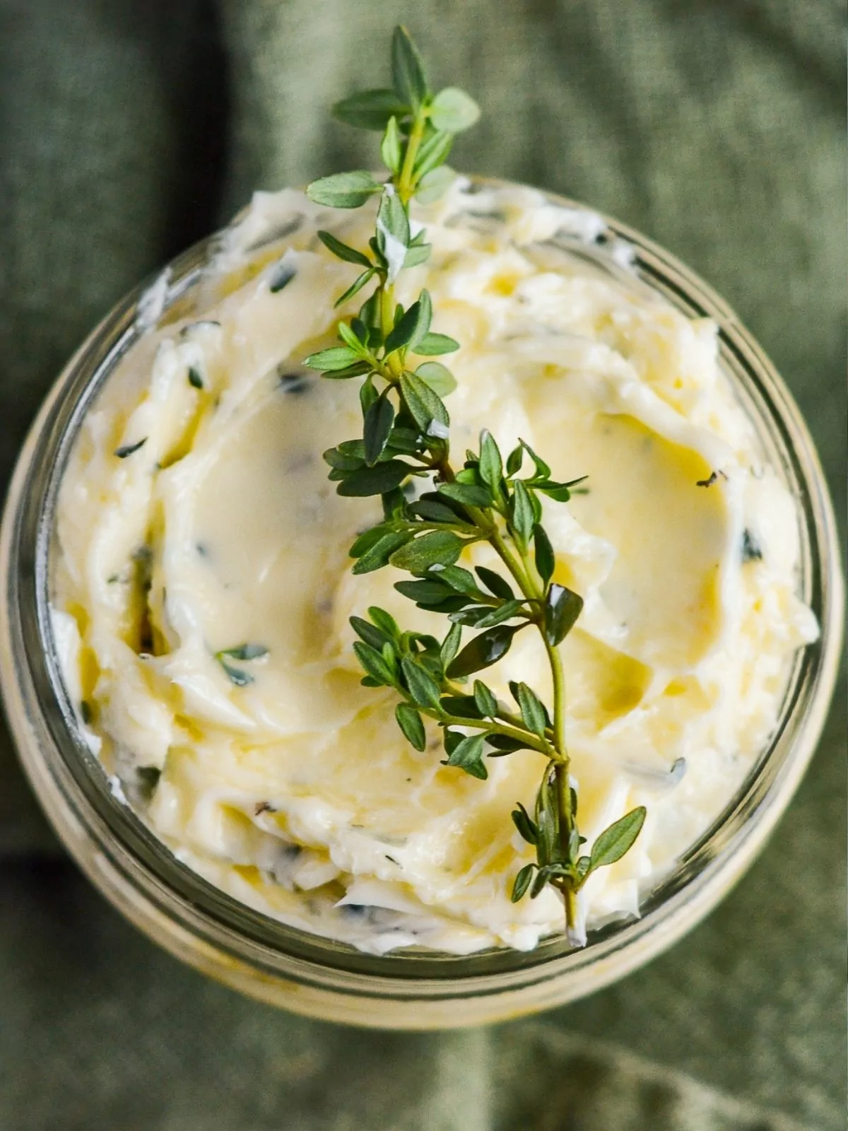 sprig of rosemary on top of mason jar with butter.