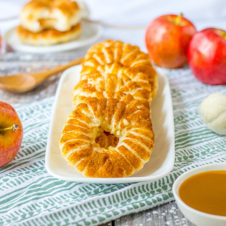 Apple rings wrapped in puff pastry served on a white rectangular platter