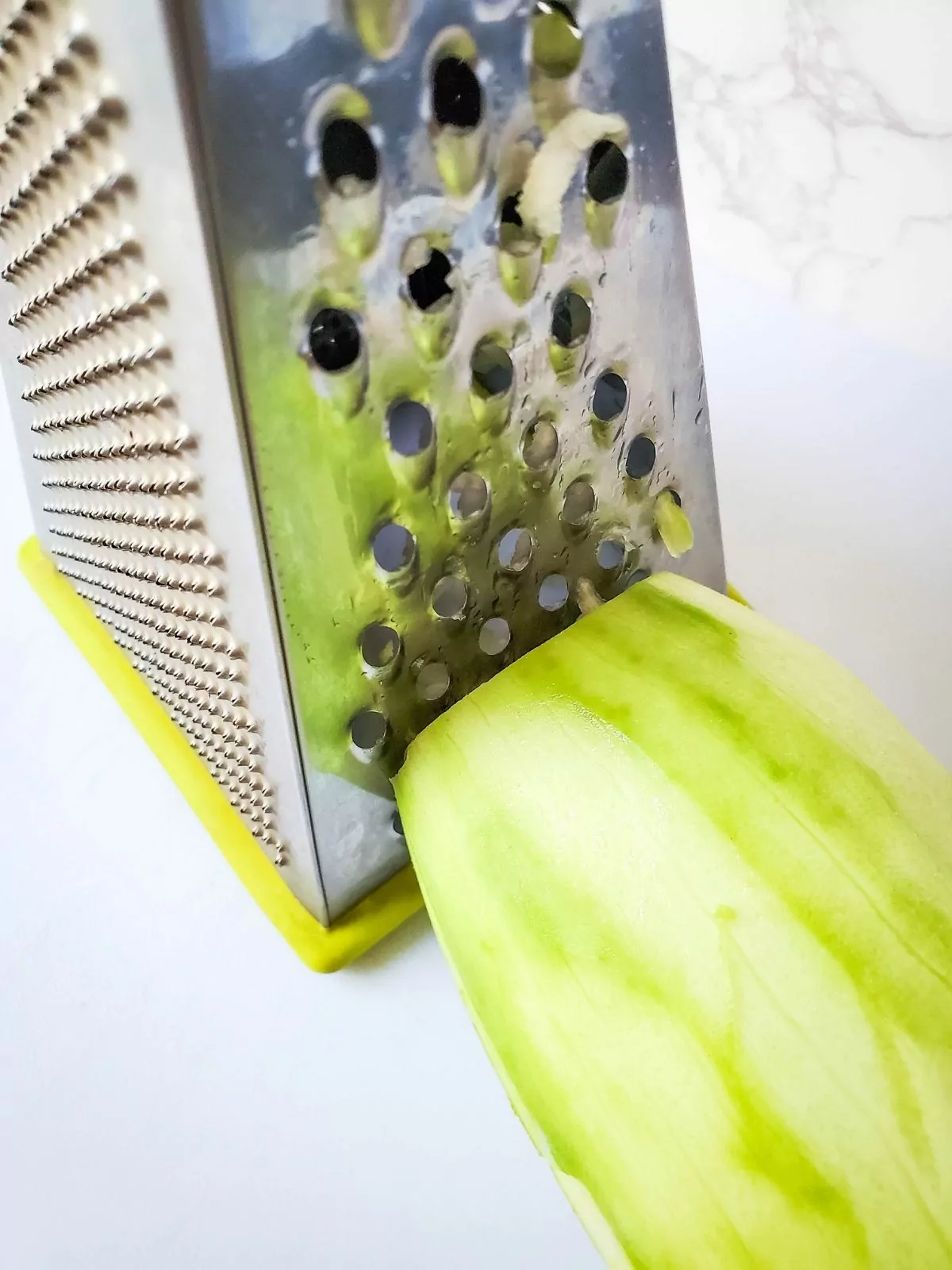 using a box grater to grate zucchini.