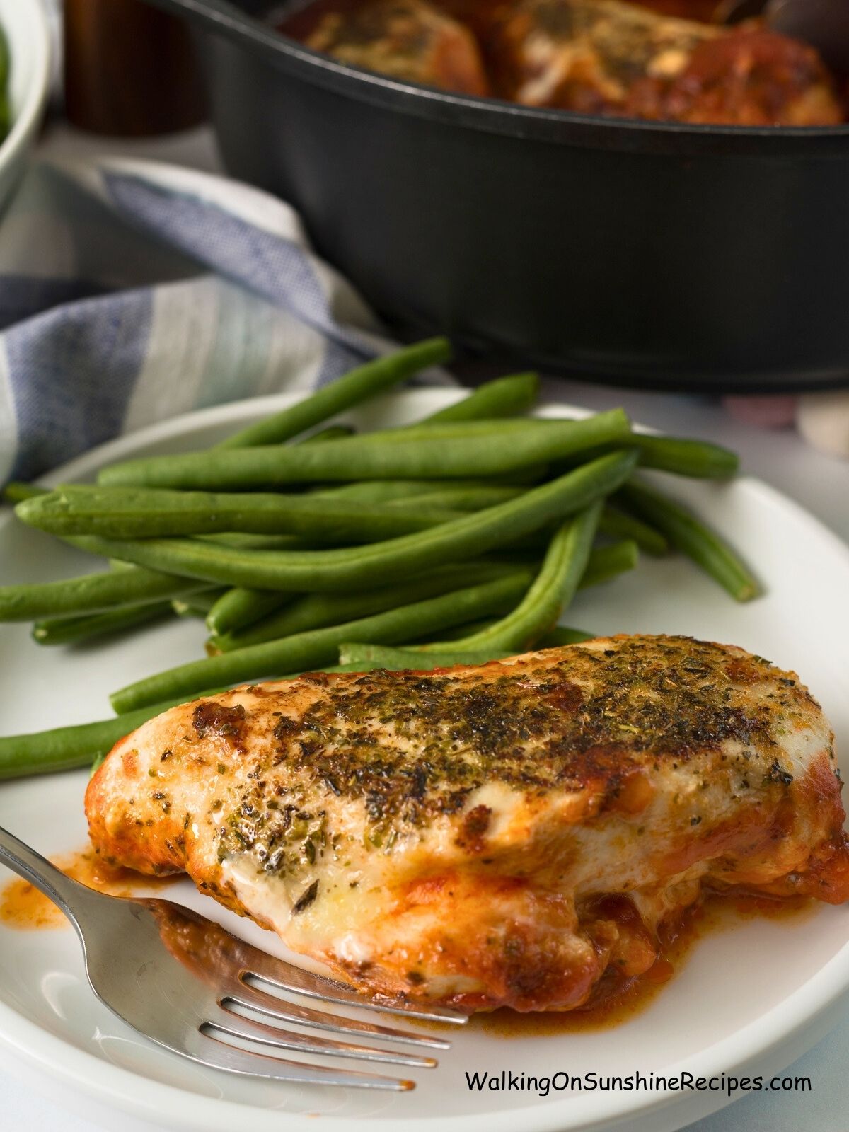 chicken breast on plate with green beans and fork.
