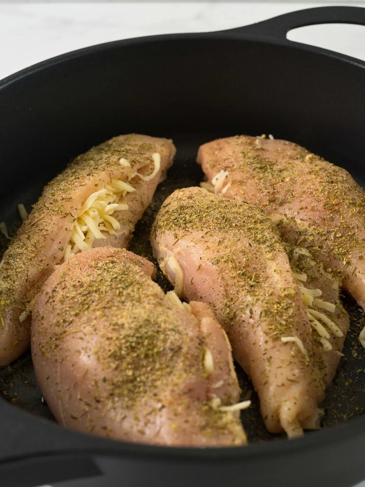 chicken breasts with cheese in cast iron pan.