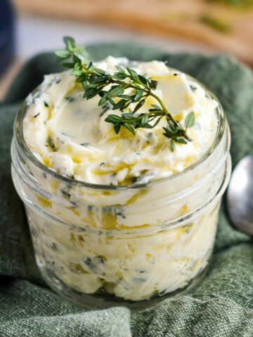 herb butter in small mason jar on green cloth.