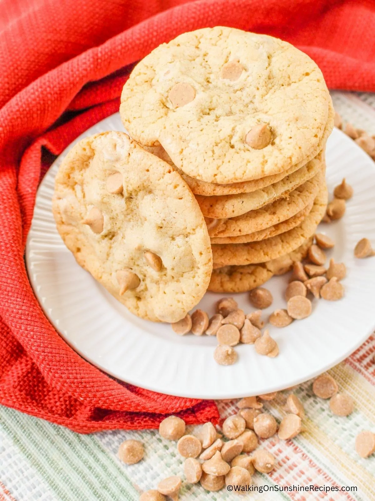 stacked cookies on plate with peanut butter chips scattered around.