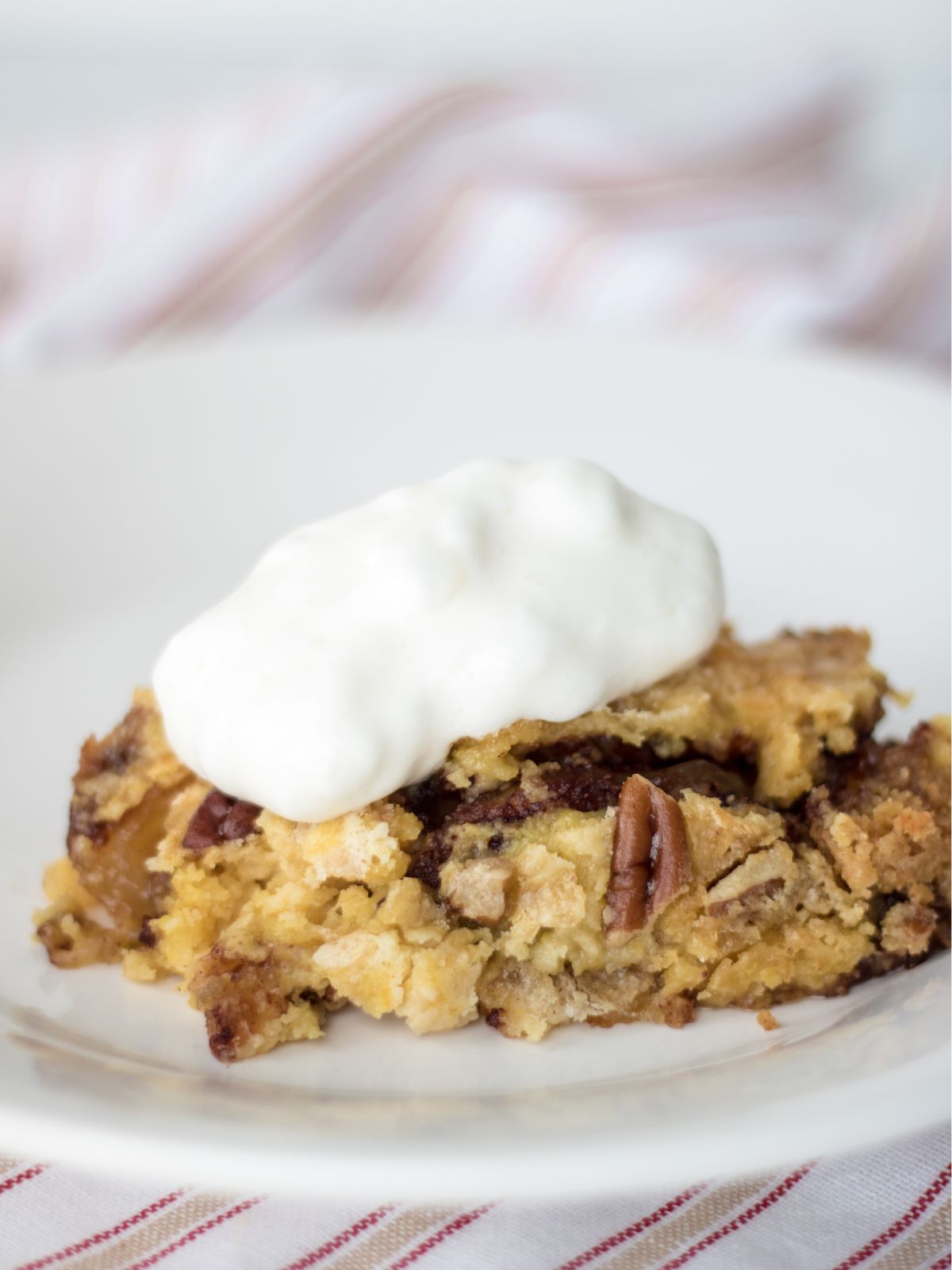 apple dump cake with whipped cream on plate.