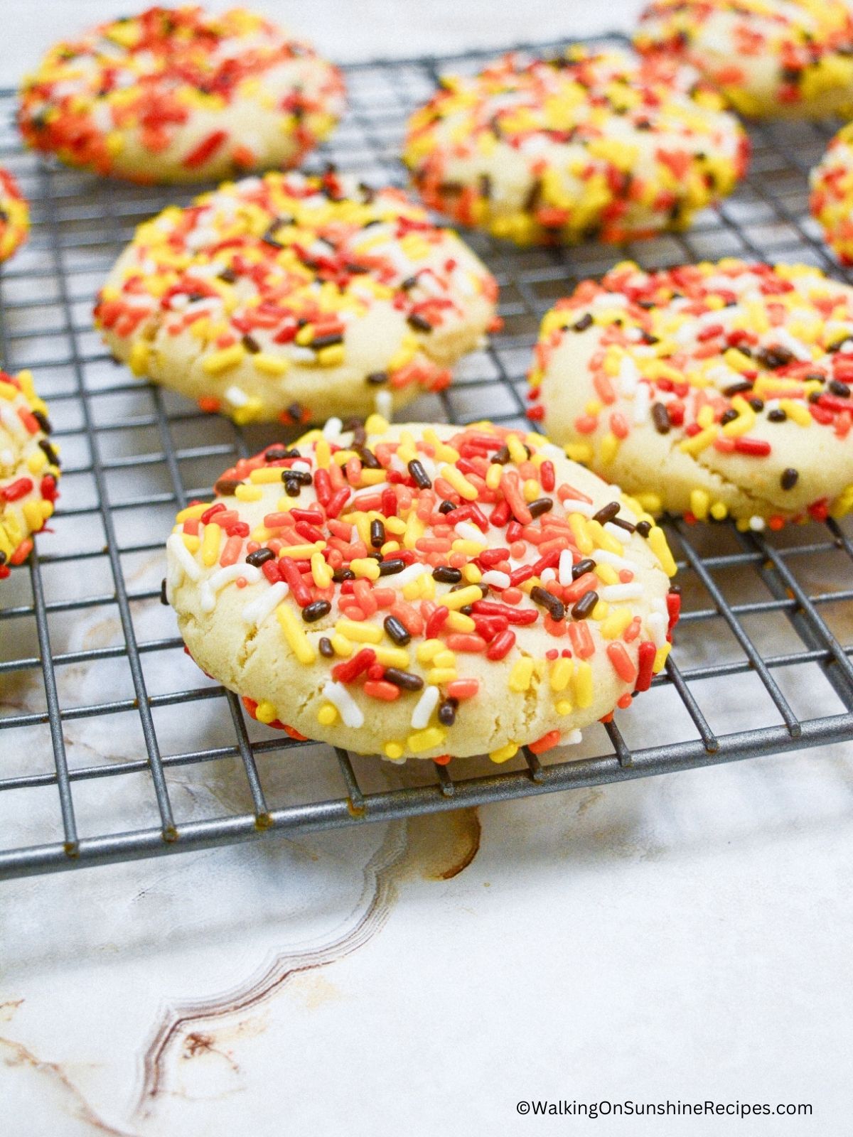 Sprinkle cookies with Halloween colors on cooling rack.