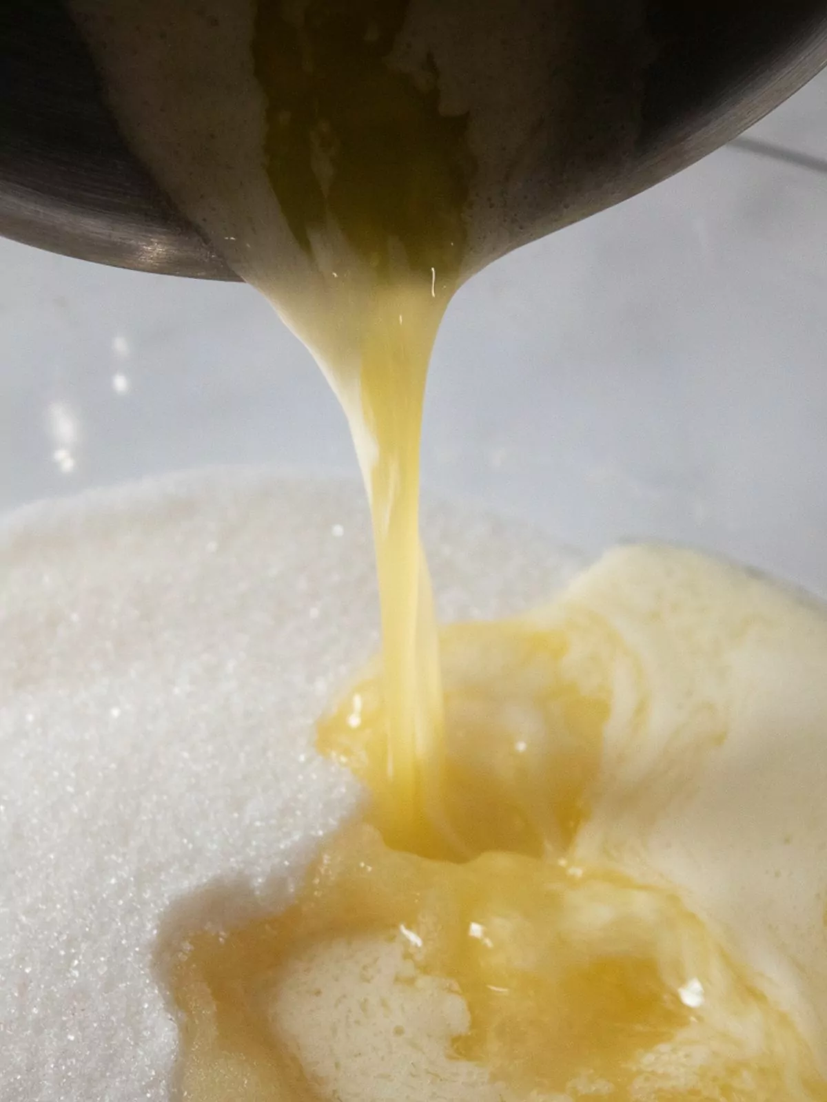 melted butter being poured in bowl of sugar.