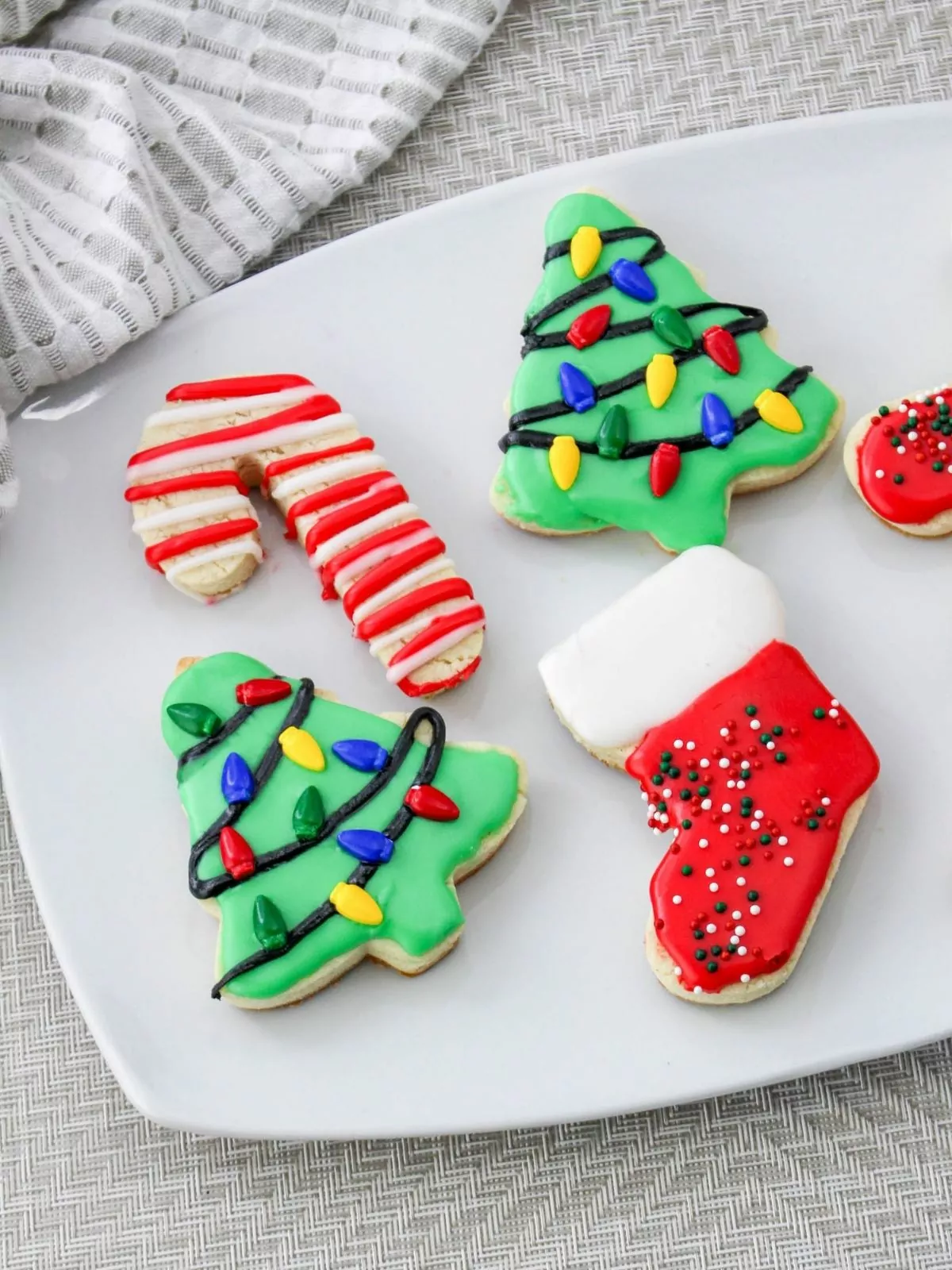 decorated Christmas cutout cookies on white plate.