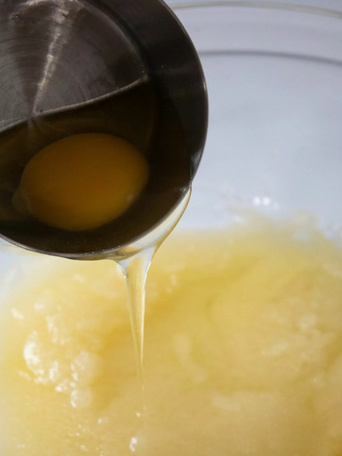 Egg being poured into butter, sugar mixture.