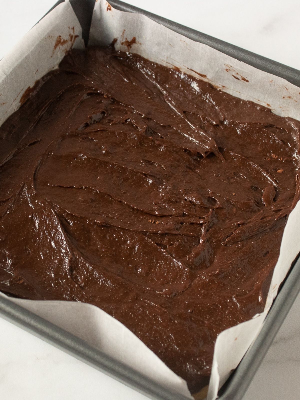 chocolate brownie layer in pan with parchment paper.