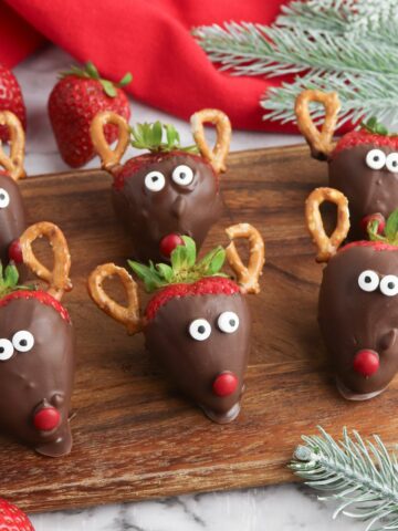 reindeer snack from strawberries and pretzels on cutting board.