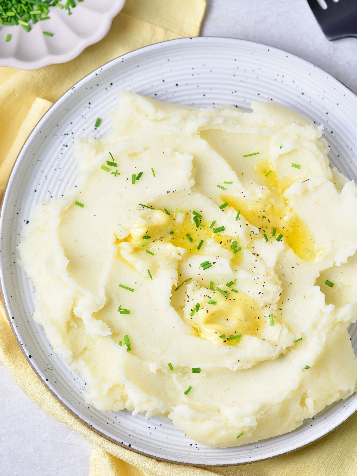 mashed potatoes recipe on plate with chopped chives and butter.