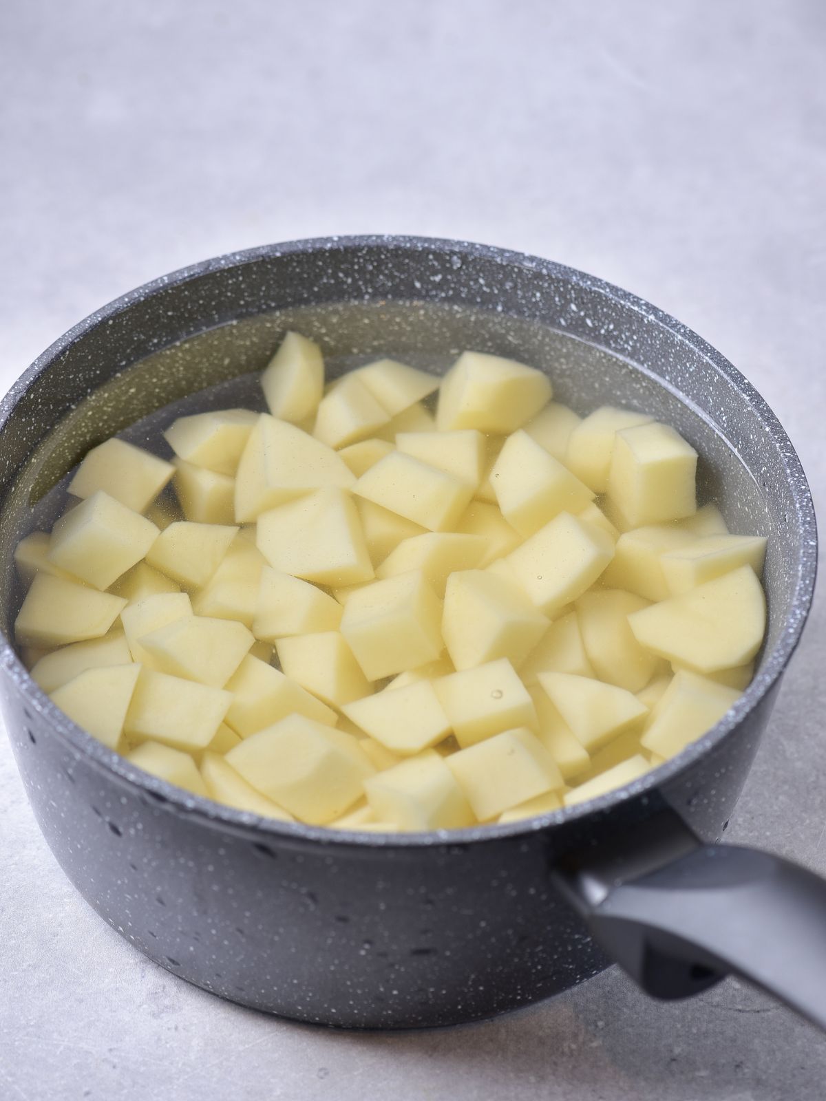 peeled quartered potatoes in pot of water.