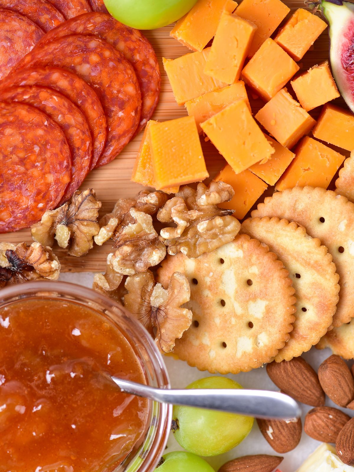 closeup of chutney, fruit, crackers, walnuts for cheese board.