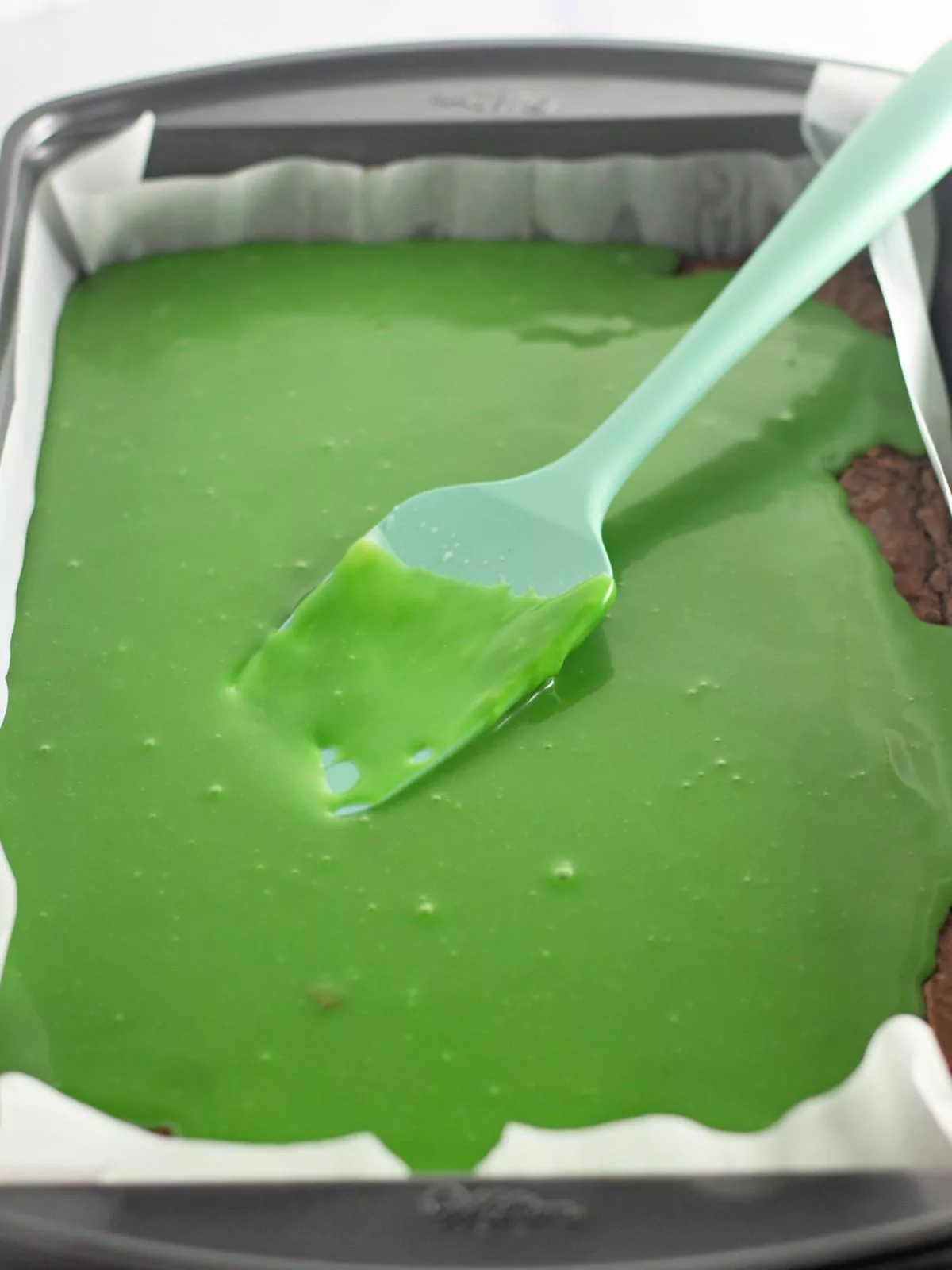 Add green frosting to the top of baked brownies.