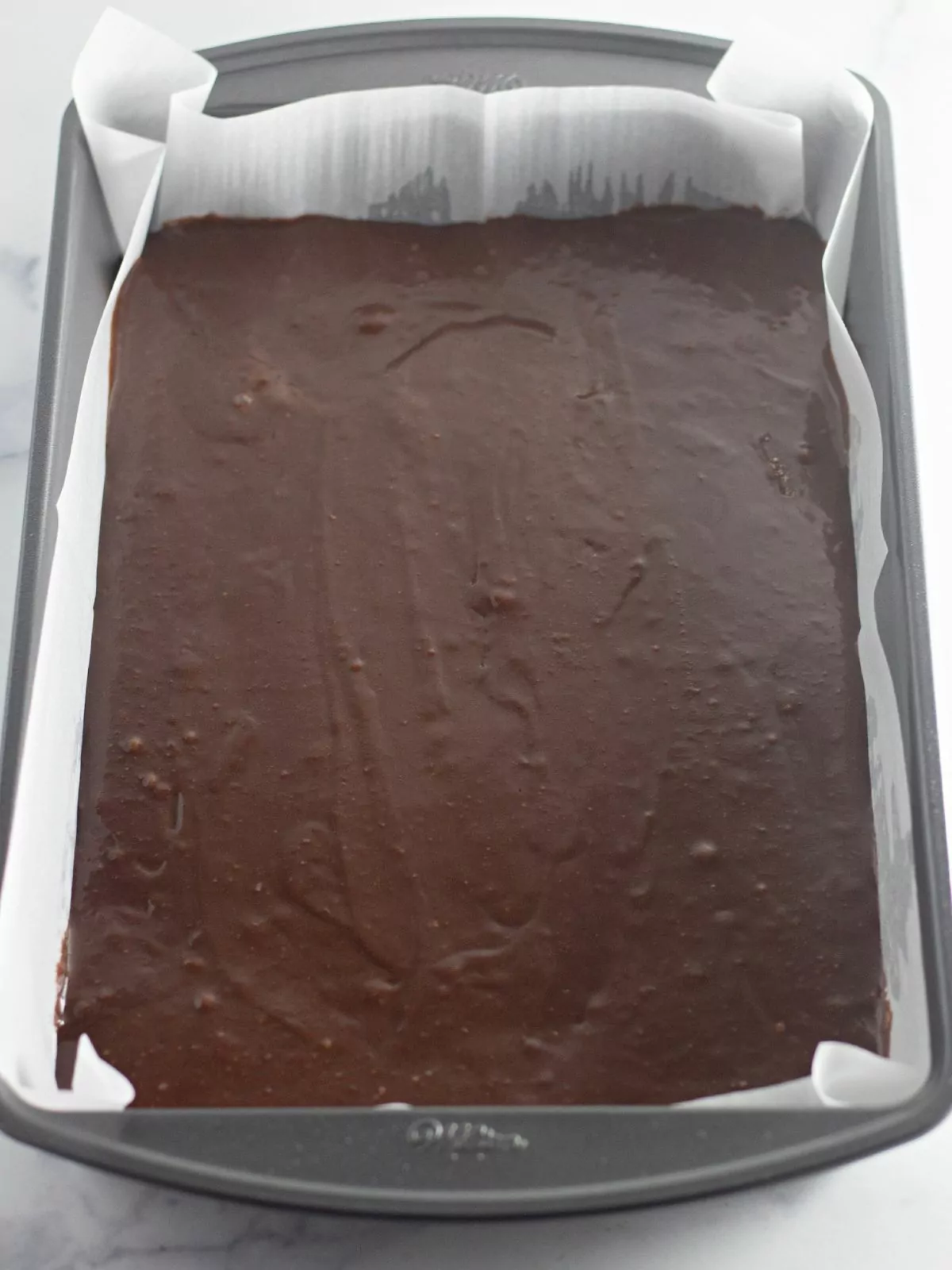 brownie batter in pan with parchment paper.