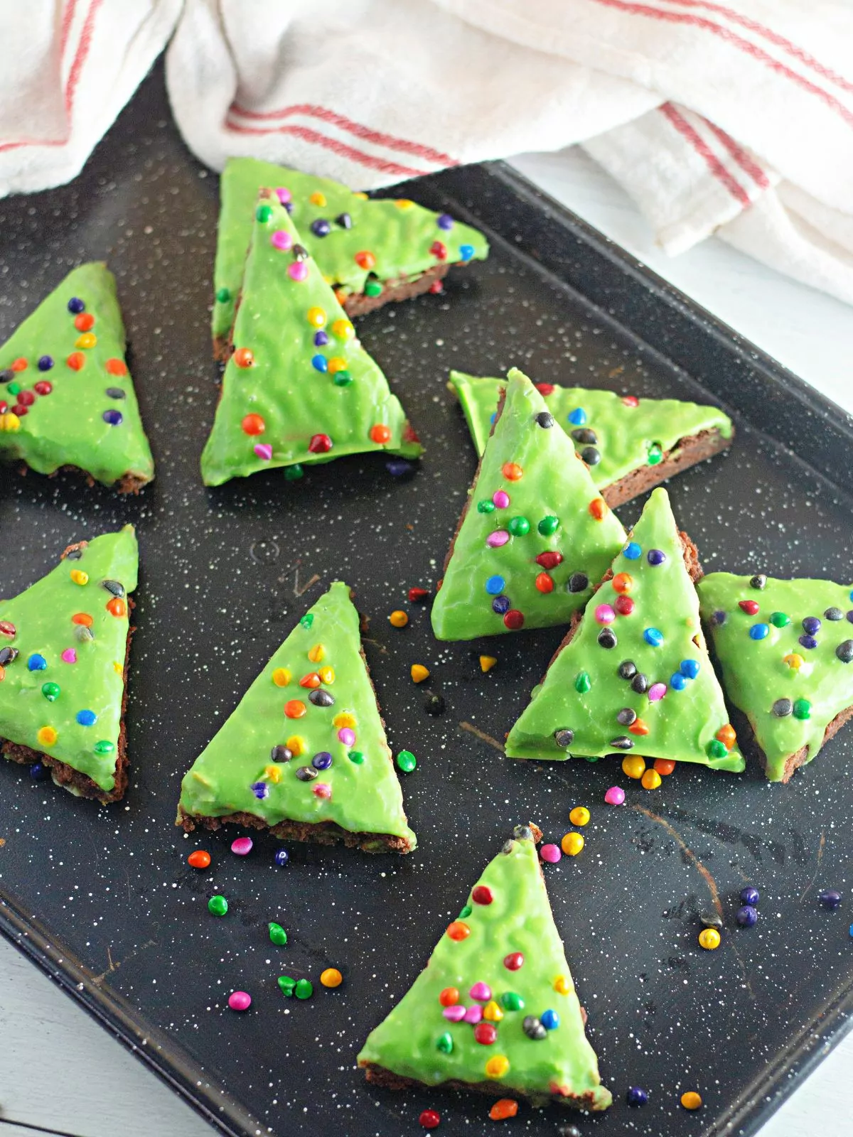 Christmas tree brownies with green frosting on tray.