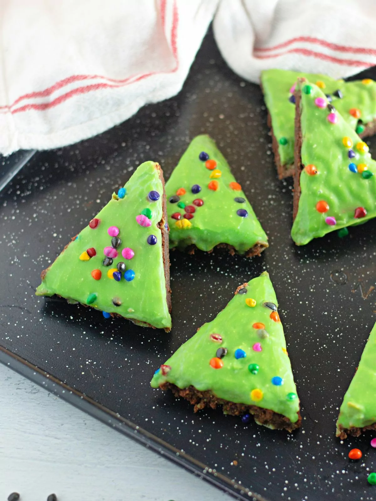 Christmas tree brownies decorated with green chocolate on baking tray.