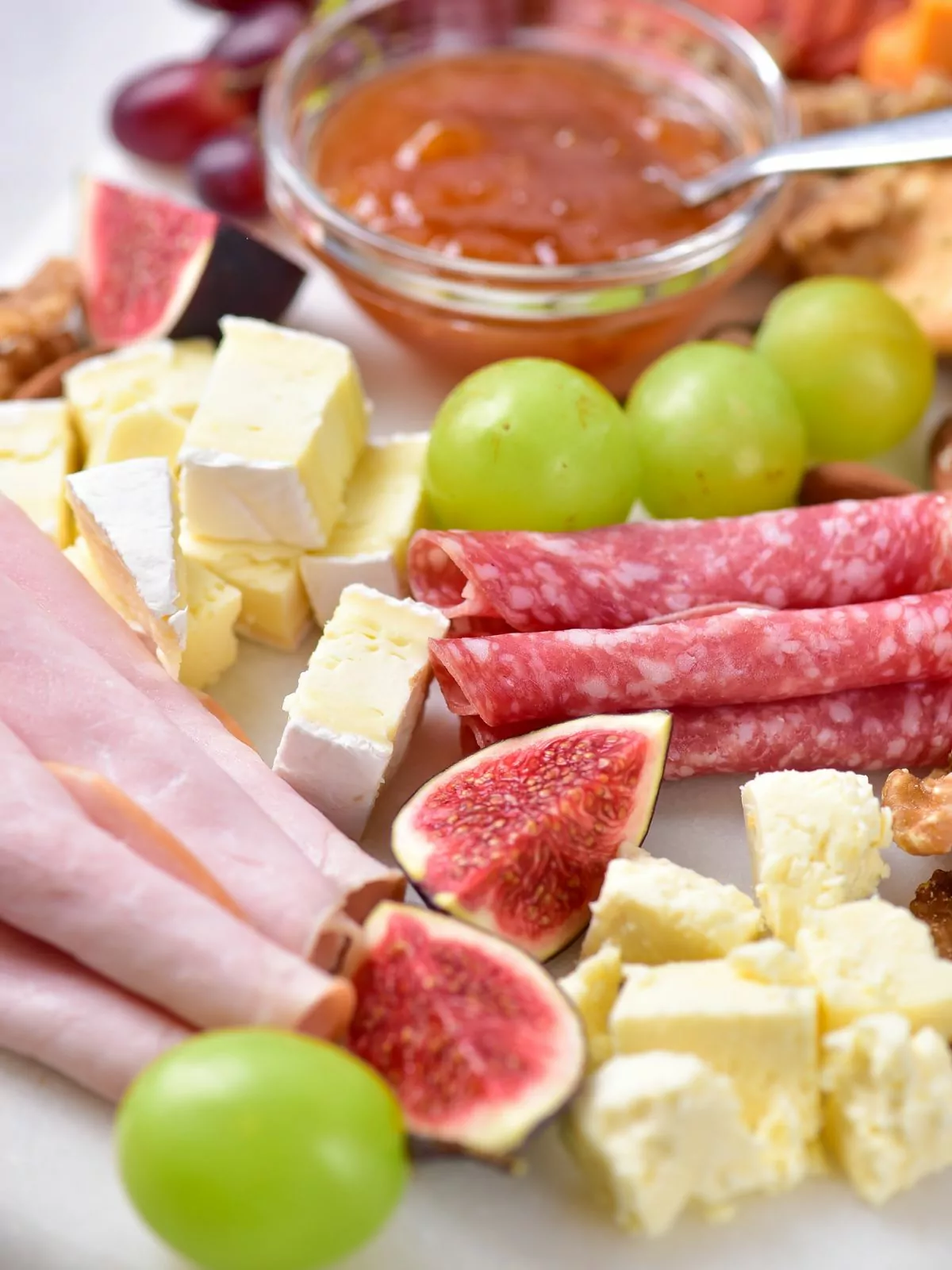 closeup of figs, cheese, ham. grapes for cheese board.