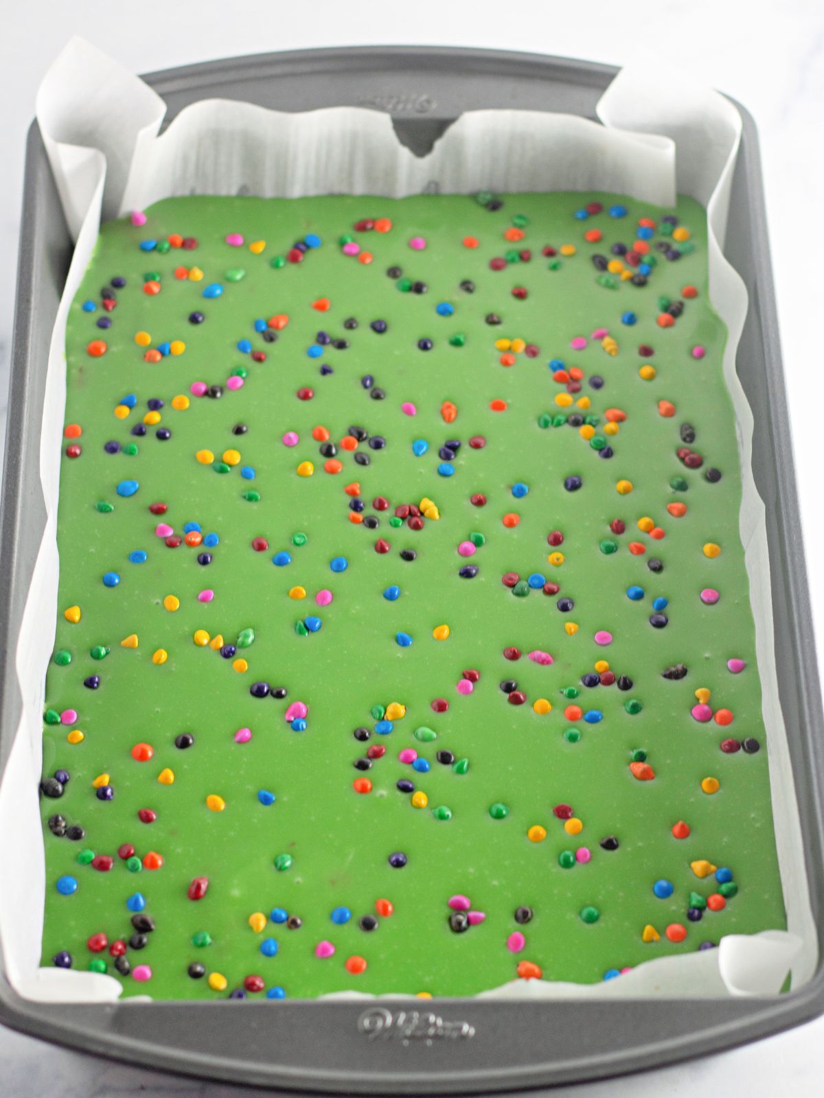 decorated brownies with green frosting and colorful chips.