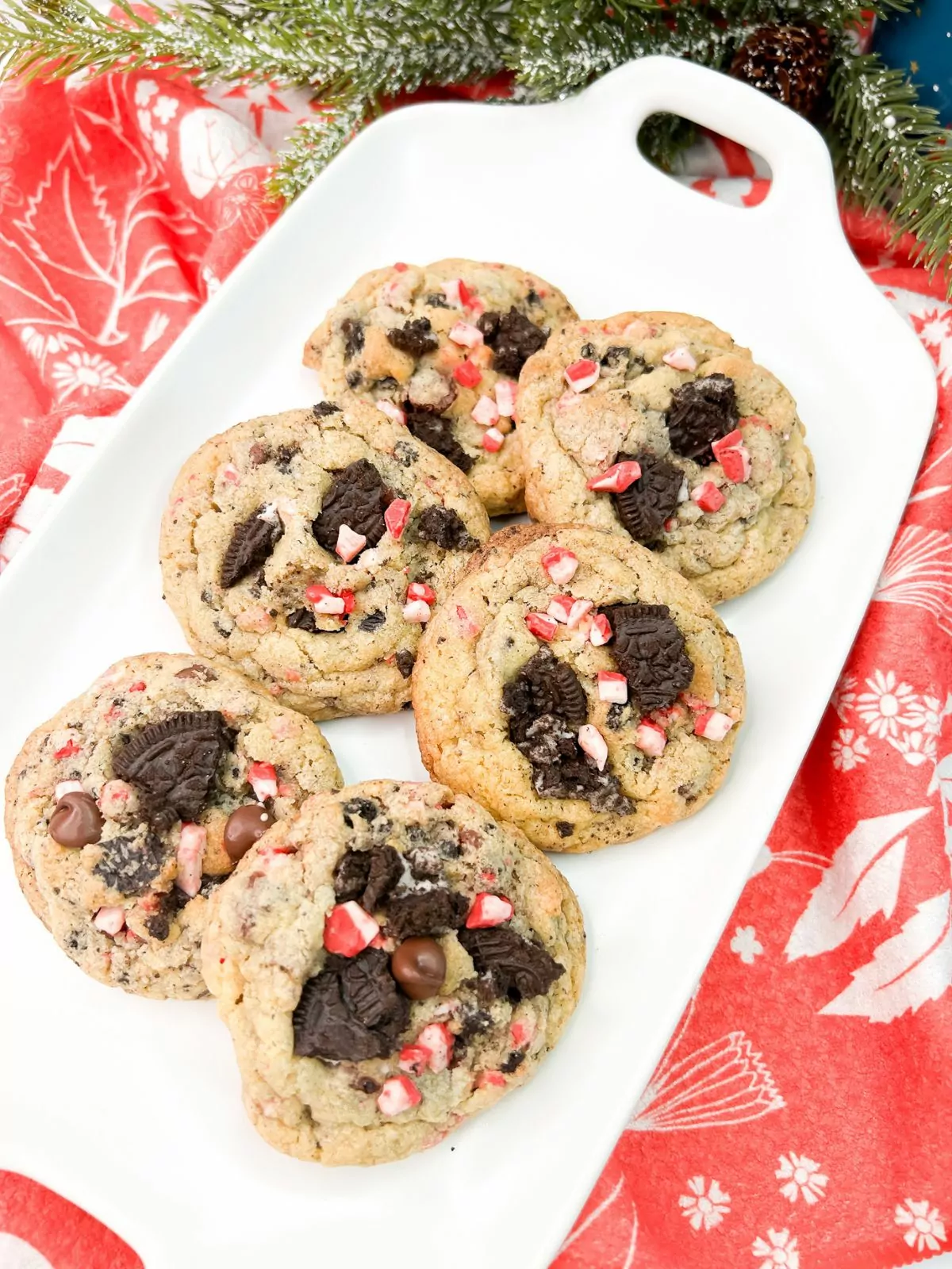 Christmas cookies with chunks of Oreo cookie crumbs and peppermint chips on white tray.