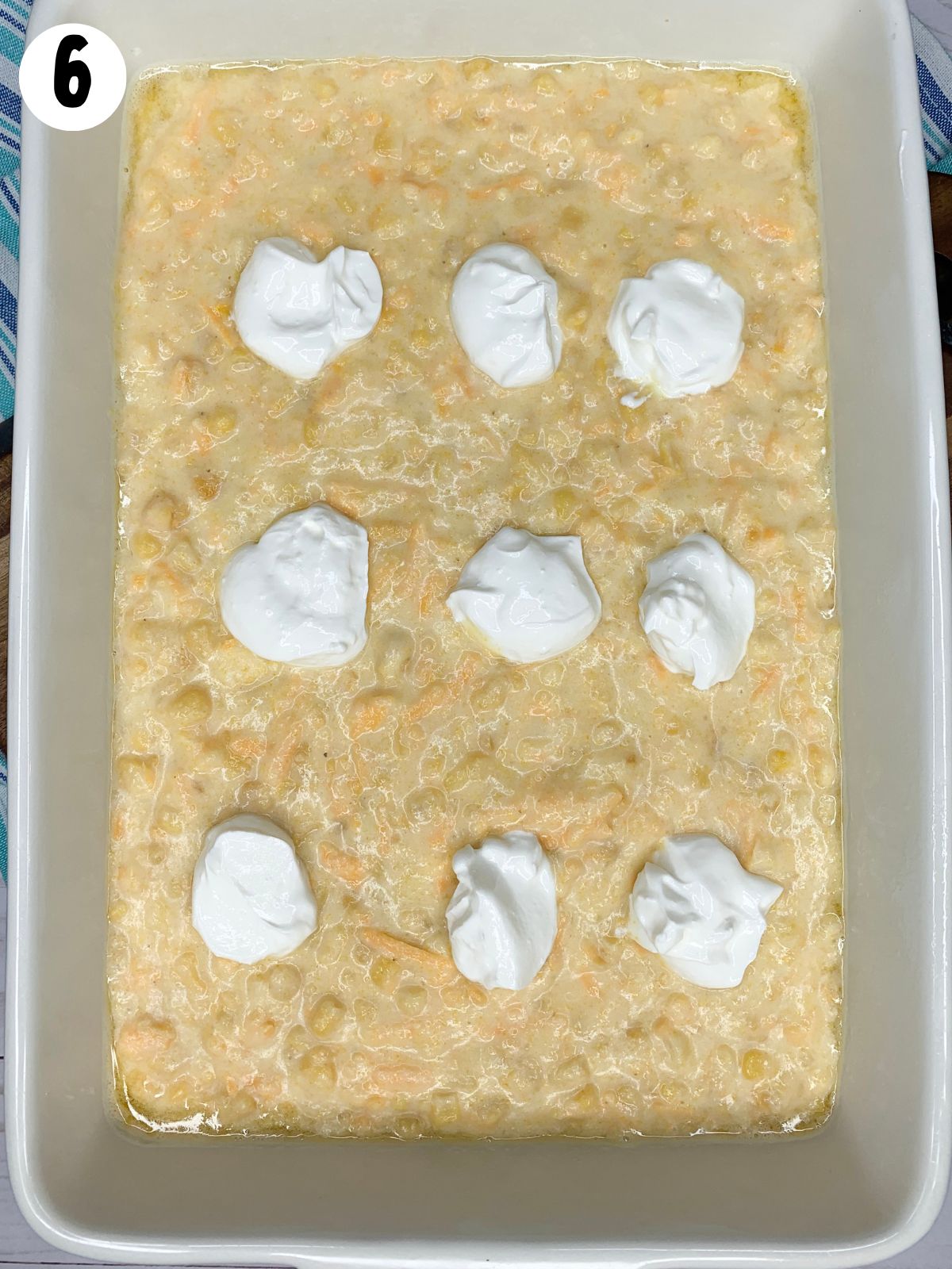 Add sour cream to top of corn pudding casserole.